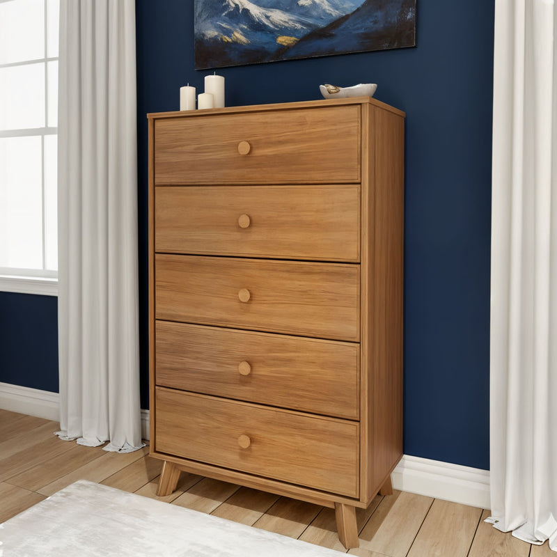 Mid-century modern tall five-drawer oak dresser chest of drawers in natural wood finish against a navy blue accent wall, styled in a bedroom with white curtains and hardwood floor