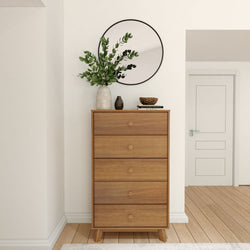 Modern wooden dresser with plants and decorative items, placed under a round mirror in a contemporary room.