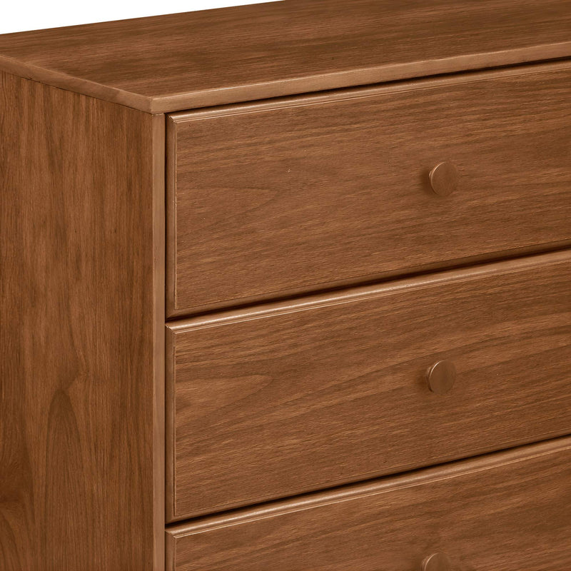Close-up of brown wooden 3-drawer dresser with round knobs and visible wood grain, bedroom storage furniture in mid-century modern style