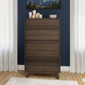 Mid-century modern tall five-drawer walnut dresser chest of drawers in a styled navy blue bedroom with hardwood floors, white curtains, decorative candles, ceramic bowl and mountain wall art