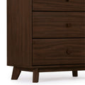 Close-up of dark walnut mid-century modern wooden dresser chest of drawers showing lower drawers with round knobs, visible wood grain texture and tapered legs