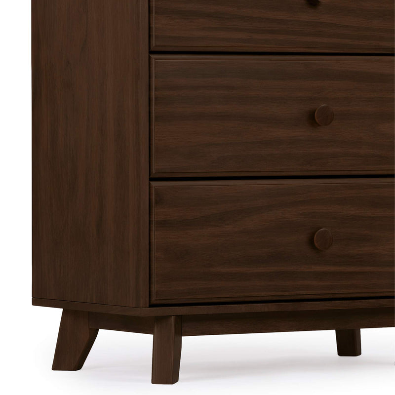 Close-up of dark walnut mid-century modern wooden dresser chest of drawers showing lower drawers with round knobs, visible wood grain texture and tapered legs