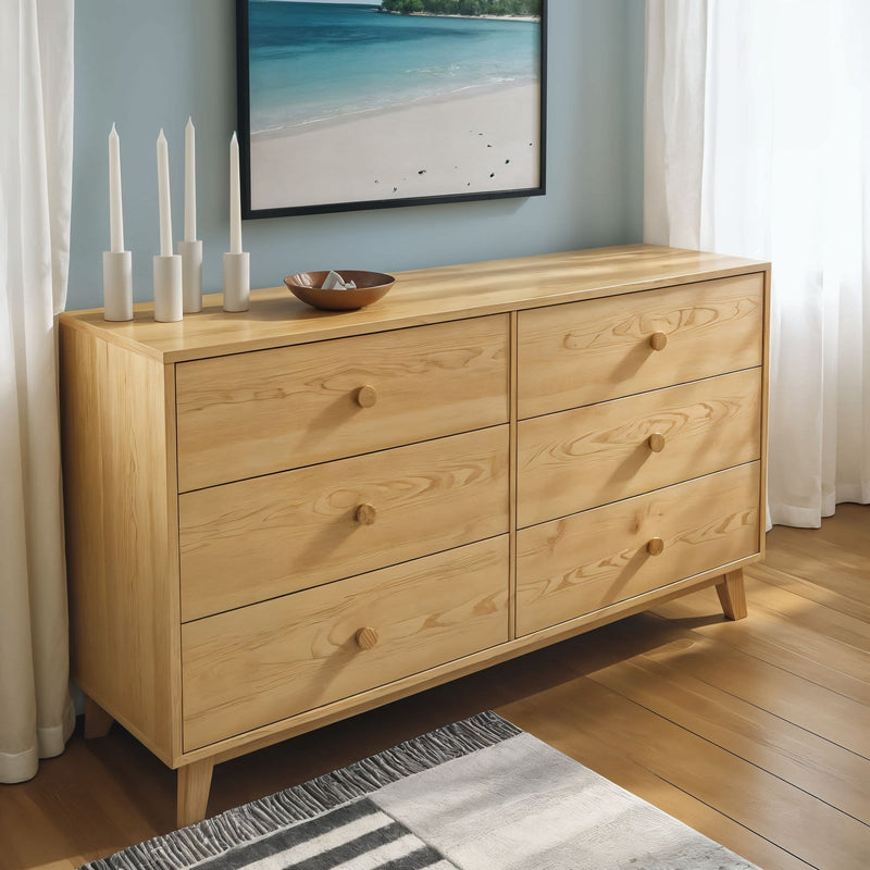 Light oak six-drawer mid-century dresser in bright bedroom with coastal wall art, candles and wooden bowl, natural wood storage