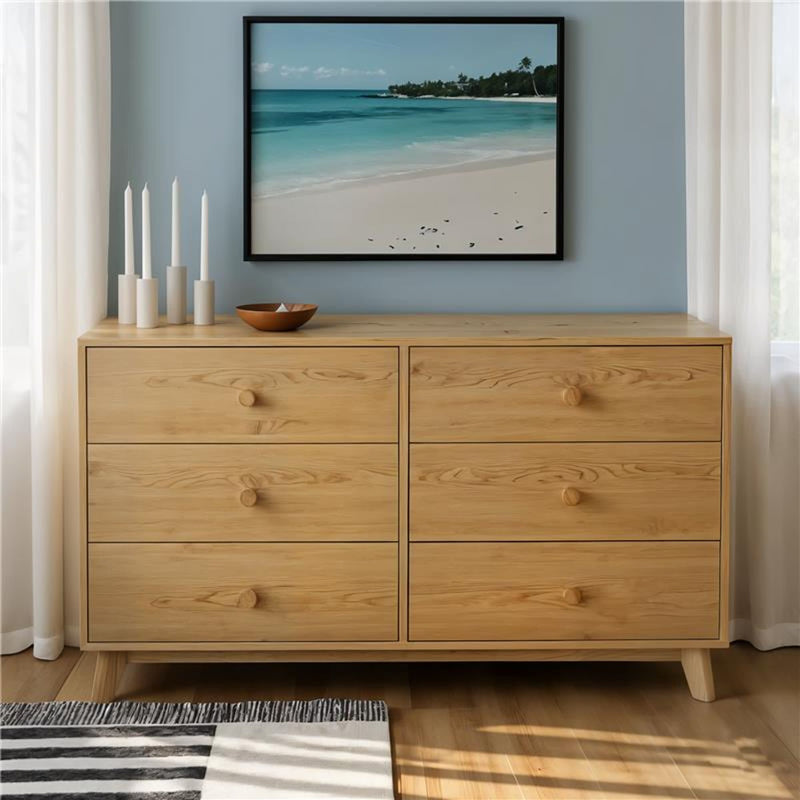 Oak six-drawer dresser with round knobs in a minimalist mid-century modern bedroom, beach wall art, candles and hardwood floor