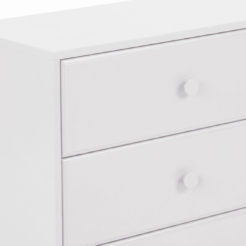 Close-up of modern white dresser drawers with round knobs, minimalist bedroom storage chest