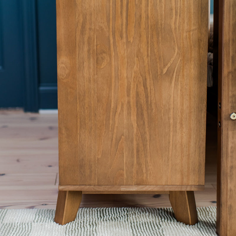 Mid-century modern wooden cabinet with natural grain details on a striped rug in a home interior setting.