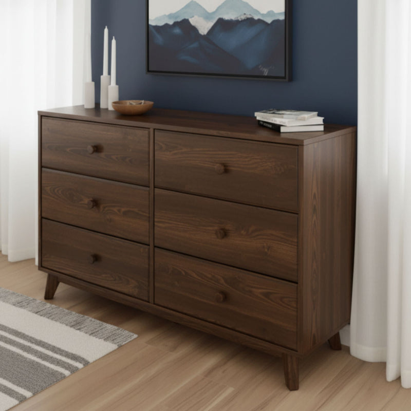 Mid-century modern walnut 6-drawer dresser with tapered legs, staged in a bedroom with navy accent wall, hardwood floor, candles and framed art