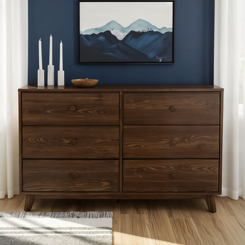 Mid-century modern walnut 6-drawer dresser for bedroom storage with blue accent wall, framed mountain artwork, white curtains and hardwood floor