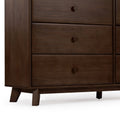 Close-up of mid-century modern solid wood dresser in dark walnut finish showing three drawers, round wooden knobs and angled legs