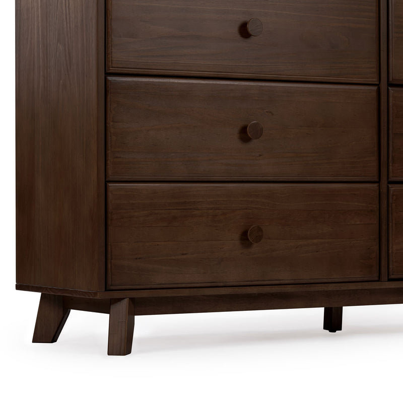 Close-up of mid-century modern solid wood dresser in dark walnut finish showing three drawers, round wooden knobs and angled legs