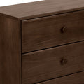 Close-up of a dark brown solid wood dresser with three drawers and round knob handles, smooth wood-grain finish on a modern bedroom chest of drawers