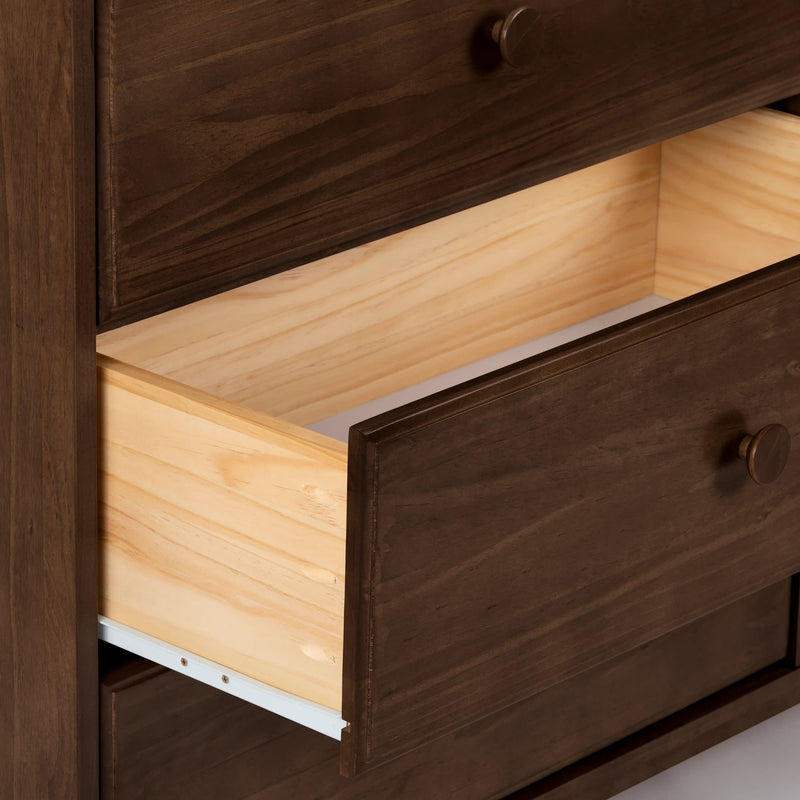 Open wooden dresser drawer with dark brown finish and natural pine interior, round wood knobs and metal slide, close-up of bedroom storage furniture