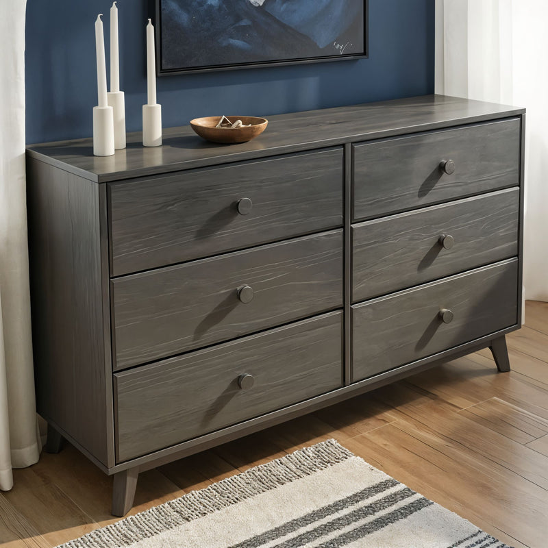Mid-century modern gray six-drawer wooden dresser on hardwood floor, styled with white candles and a decorative bowl against a blue wall