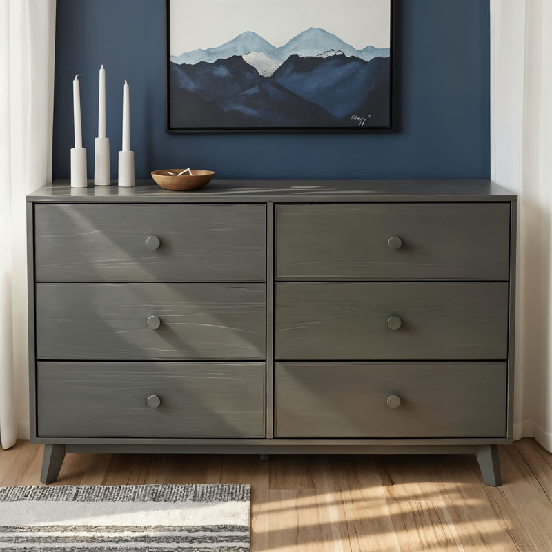 Gray six-drawer wooden dresser against blue accent wall with mountain artwork, white candles and decorative bowl — modern bedroom storage