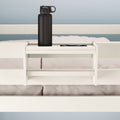 White bed with a convenient built-in shelf holding a black water bottle, perfect for optimizing bedroom storage and organization.