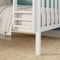 Close-up of white wooden bed rail with beige linen blanket and natural jute rug – modern nursery decor