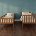 Two wooden twin beds with white bedding in a minimalist kids' bedroom against a teal textured accent wall and dark hardwood floor