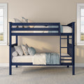 Navy blue twin-over-twin bunk bed with white and blue bedding, ladder and decorative pillows in a bright kids' bedroom with beige walls and windows
