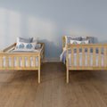 Two wooden twin beds with blue-and-white bedding and leaf-print pillows in a coastal-style kids' bedroom with a light blue wall and hardwood floor