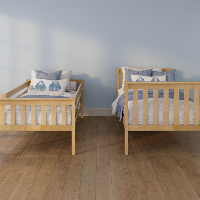 Two wooden twin beds with blue-and-white bedding and leaf-print pillows in a coastal-style kids' bedroom with a light blue wall and hardwood floor