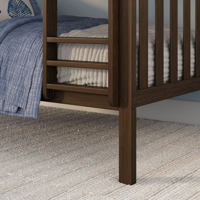 Close-up of dark walnut wooden bed frame slats and corner with blue quilted blanket, cream ribbed mattress cover and woven gray area rug