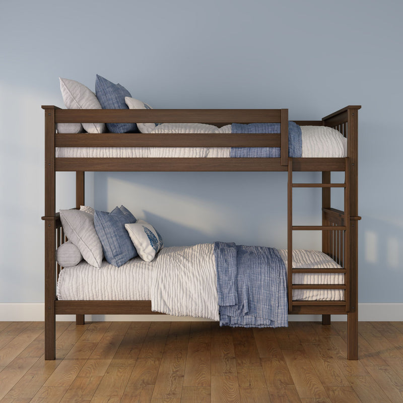 Solid wood twin-over-twin bunk bed with ladder, blue-and-white quilted bedding and pillows against a light blue wall on hardwood floors