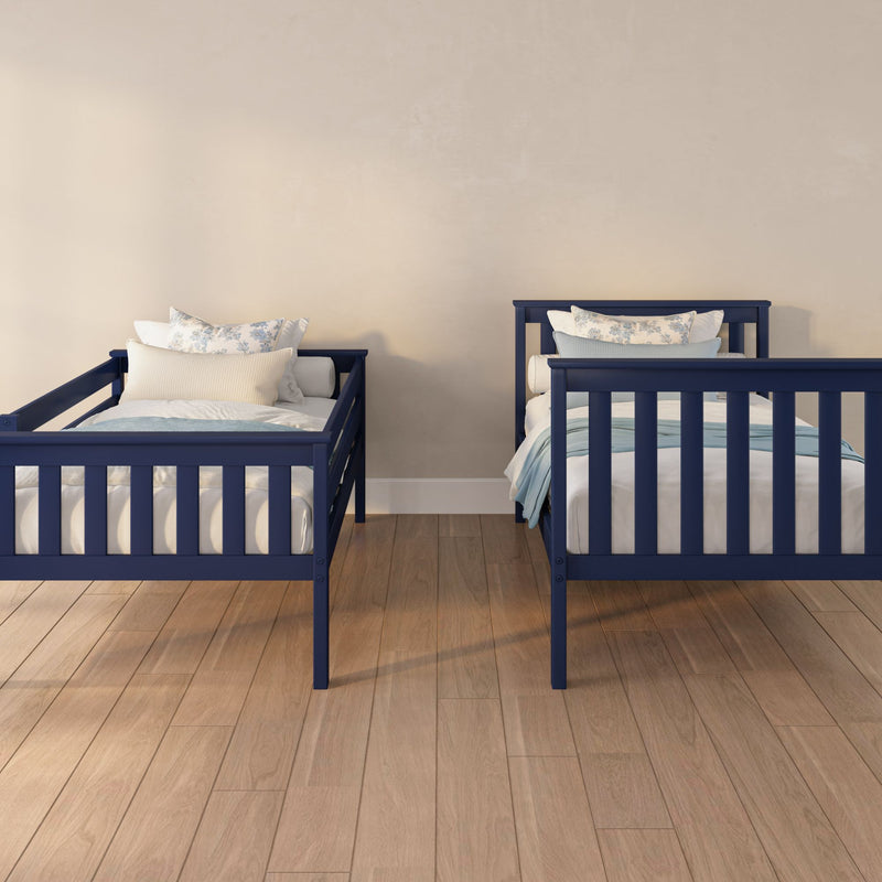 Two navy blue twin beds with white and blue floral pillows on hardwood floor against a neutral beige wall in a modern kids' bedroom nursery
