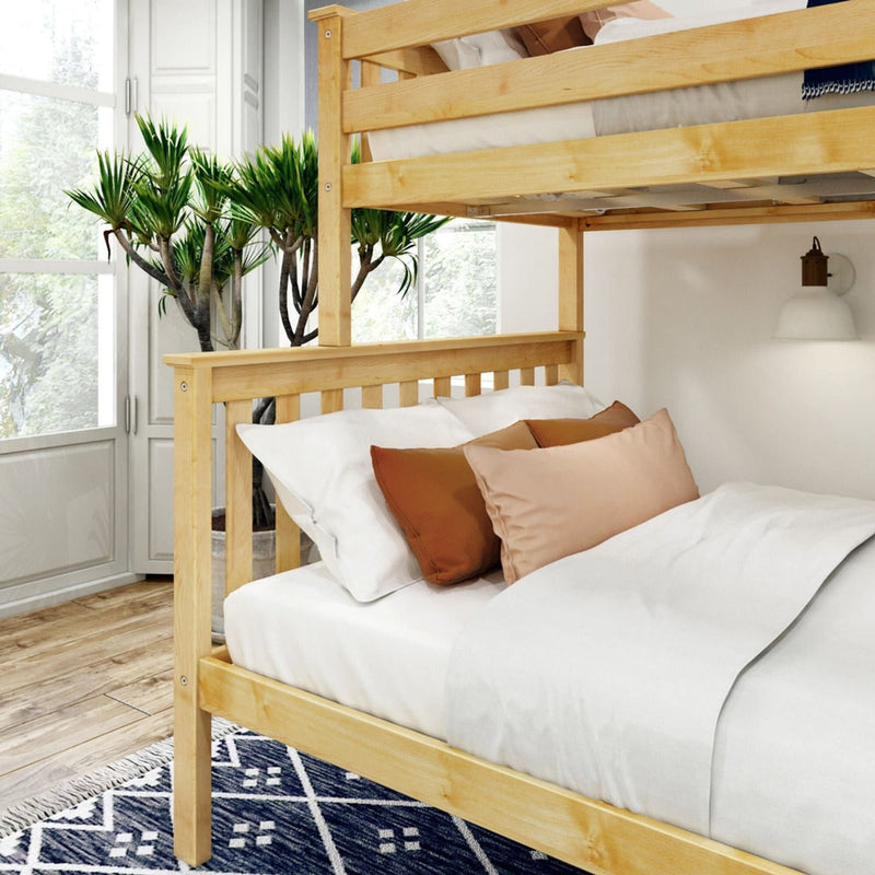 Wooden bunk bed in a bright bedroom with orange and beige pillows on white sheets, next to a large window and indoor plants.