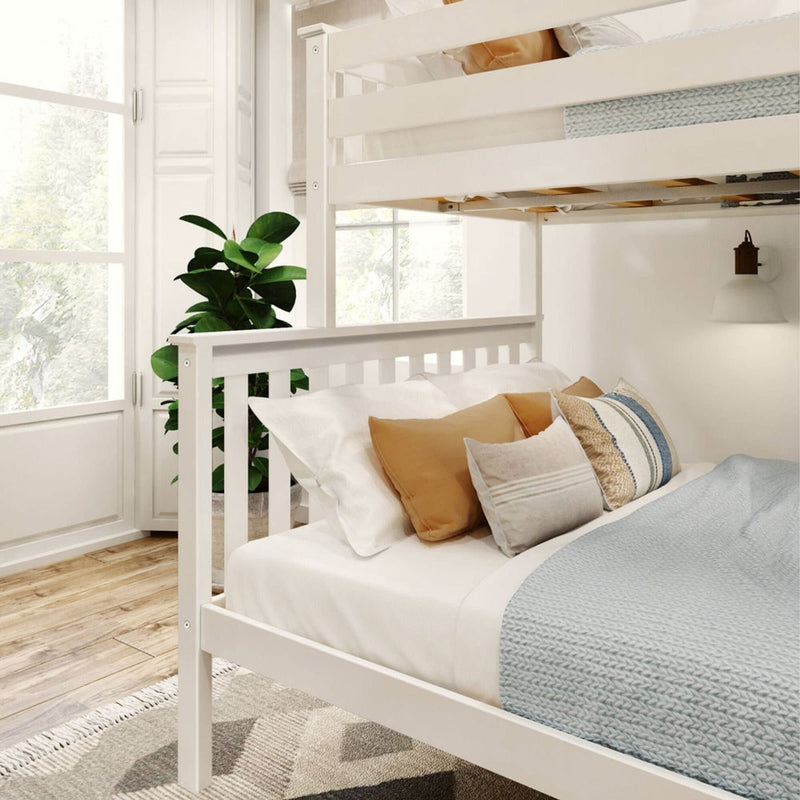 White bunk bed with cozy pillows and a blue knitted blanket in a bright modern bedroom with a potted plant and natural light.