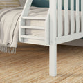 White wooden bunk bed ladder and slatted guardrail with beige linen bedding, fringed throw blanket and natural jute rug in kids' bedroom