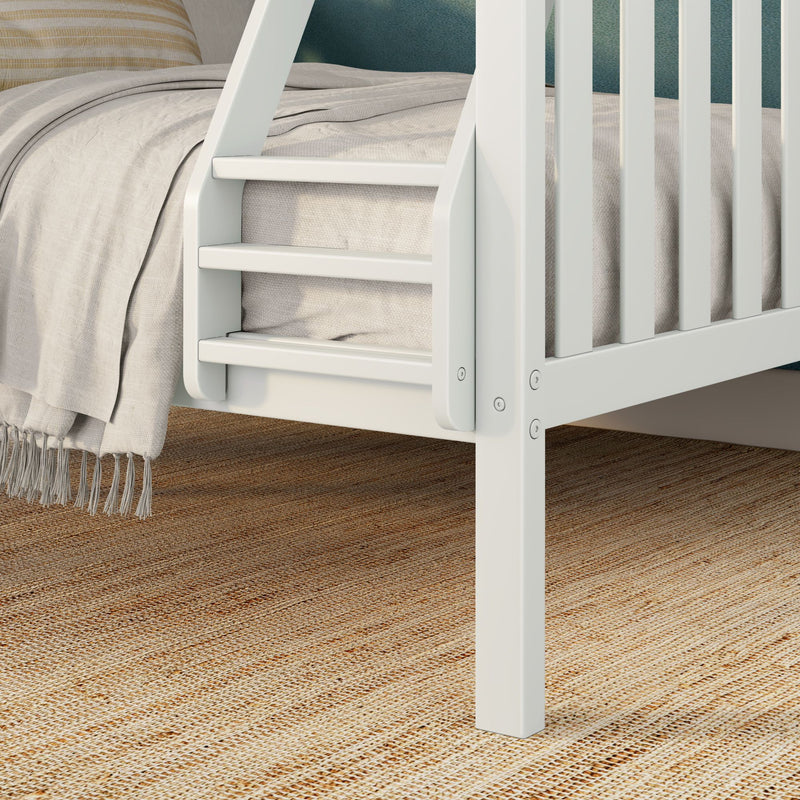 White wooden bunk bed ladder and slatted guardrail with beige linen bedding, fringed throw blanket and natural jute rug in kids' bedroom