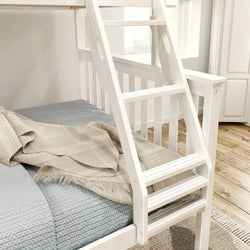 White wooden bunk bed ladder with blue and beige bedding in a bright room.