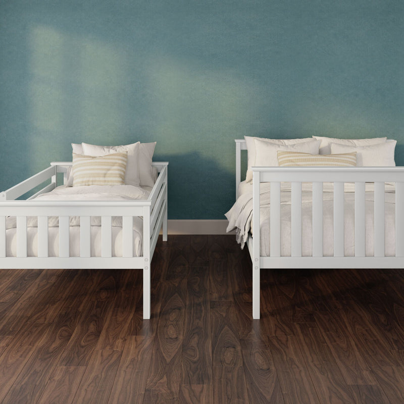 Two white wooden twin beds with neutral bedding and striped pillows against a teal textured accent wall on dark hardwood flooring