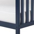 Close-up of navy blue bed frame corner with vertical slats, visible bolt hardware and white quilted mattress cover on a modern platform bed