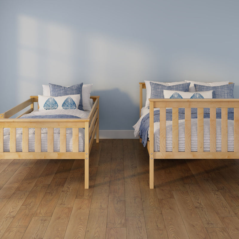 Two twin wooden bed frames with blue-and-white bedding and leaf-pattern pillows against a light blue wall on hardwood floor