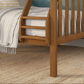 Close-up of solid oak bunk bed ladder and slatted wood rail with neutral linen bedding and woven jute rug in a modern rustic bedroom
