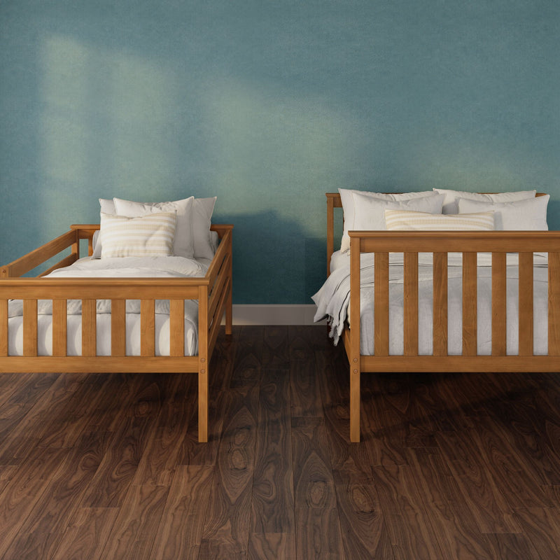Two wooden twin beds with white linens and striped pillows against a teal textured accent wall on dark hardwood flooring
