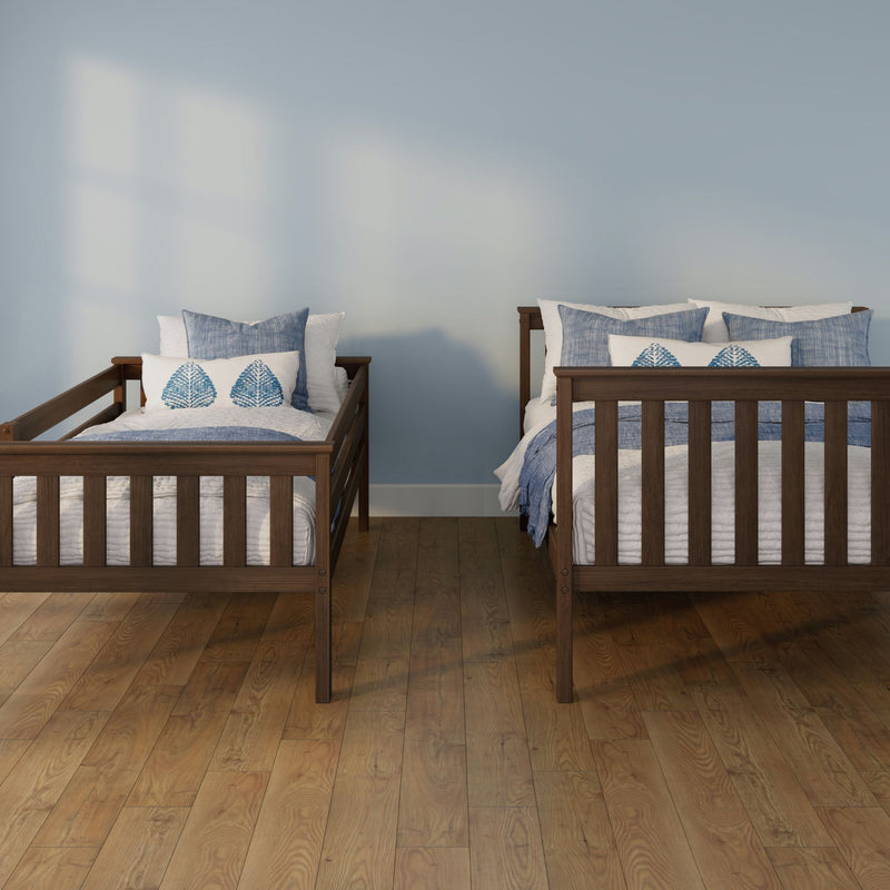 Two wooden twin beds with blue-and-white bedding and leaf-pattern pillows against a light blue wall on hardwood floors — coastal bedroom decor
