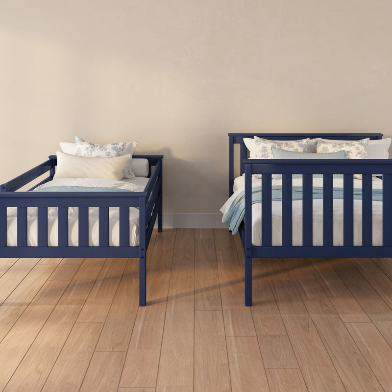 Two navy blue twin beds with floral pillows in a shared children's bedroom against a beige wall and hardwood floor