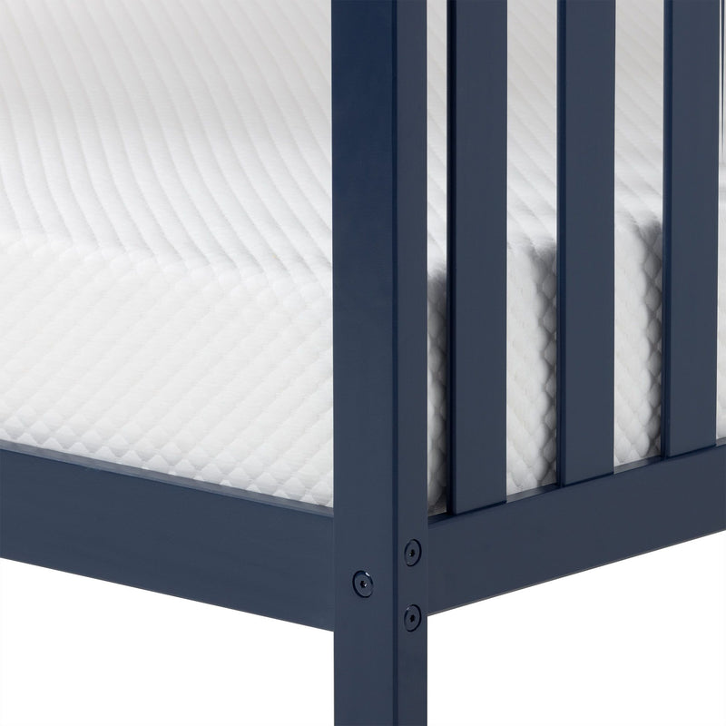 Close-up of navy blue wooden bed frame corner with white quilted mattress and slatted side rails