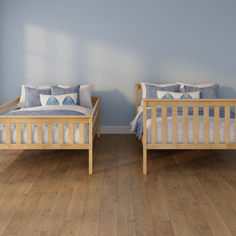 Two twin wooden beds with blue coastal bedding in a bright children's bedroom featuring a pale blue wall and hardwood floor