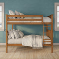 Wooden twin bunk bed with ladder, neutral linens and striped pillows against a teal textured accent wall and windows in a bright kids' bedroom