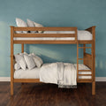 Twin-over-twin wooden bunk bed with natural wood finish, white linens and pillows against a teal textured wall on dark hardwood floor — space-saving kids’ bedroom décor