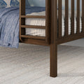 Close-up of dark walnut wooden bed frame with slatted side rails, blue quilted bedding, white mattress and textured area rug