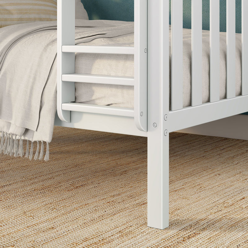 Close-up of white wooden crib corner with beige linen bedding and textured woven jute rug, modern nursery decor.