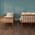 Wooden twin beds with white bedding against a teal textured wall on dark hardwood floor, modern cozy bedroom interior