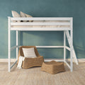 White wooden loft bed with neutral bedding and pillows above wicker lounge chair, teal textured wall and natural jute rug