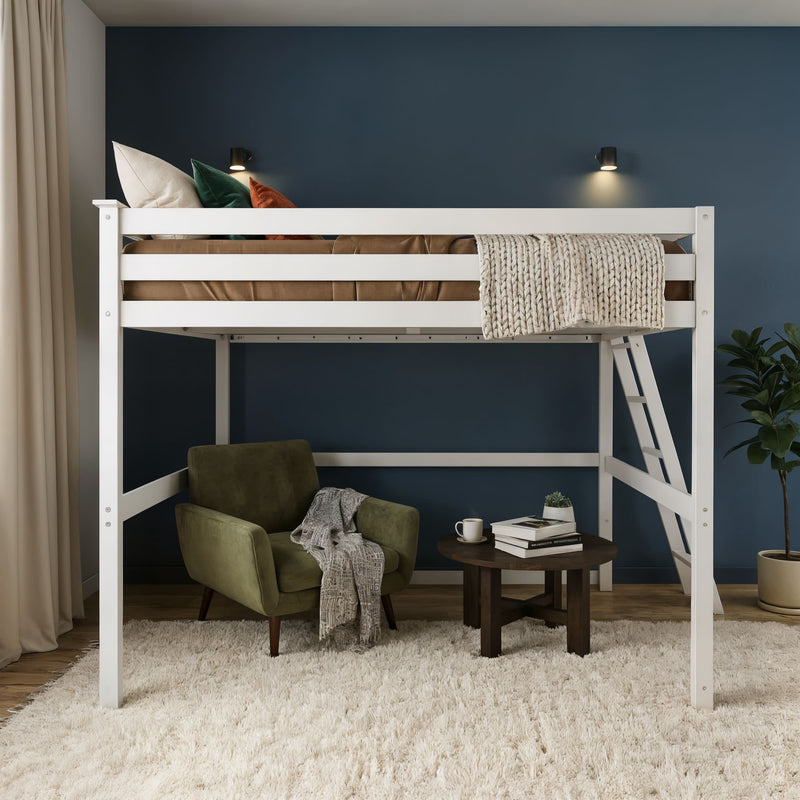 Modern white loft bed with ladder in a small bedroom, cozy reading nook with green armchair, round table, books, knit throw and navy blue accent wall