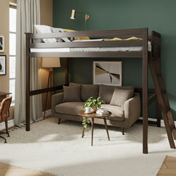 Space-saving dark wood loft bed with ladder over a cozy sofa, round coffee table and floor lamp against a green accent wall in a modern studio apartment