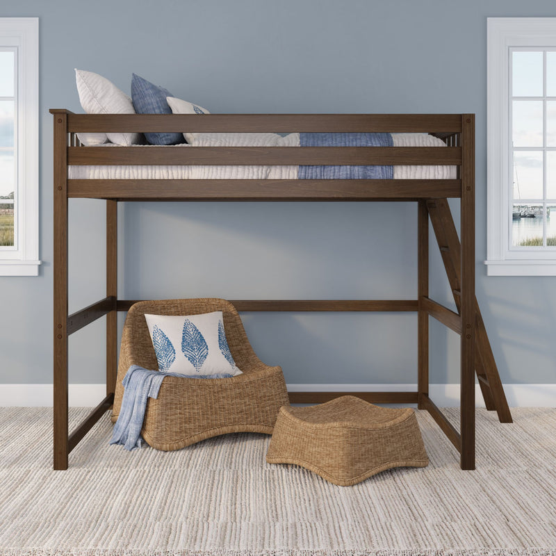 Wooden loft bed with ladder, blue bedding and pillows above woven rattan lounge chair in a coastal-style light-blue bedroom with windows